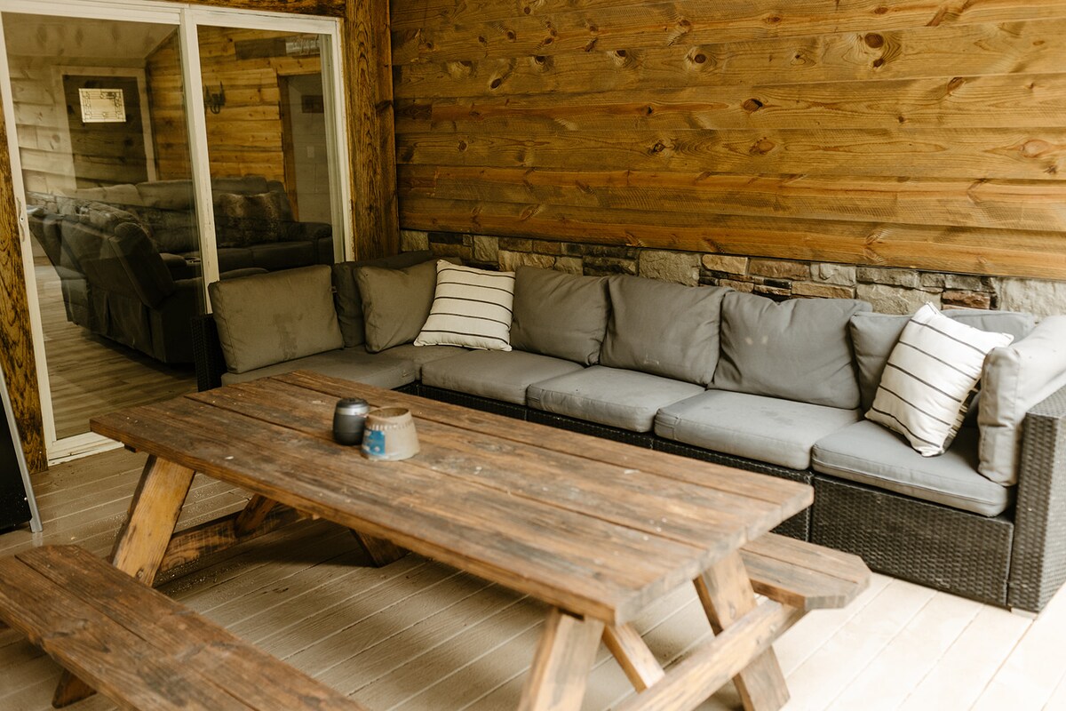 Covered deck seating with a picnic table at Running Water Cabin