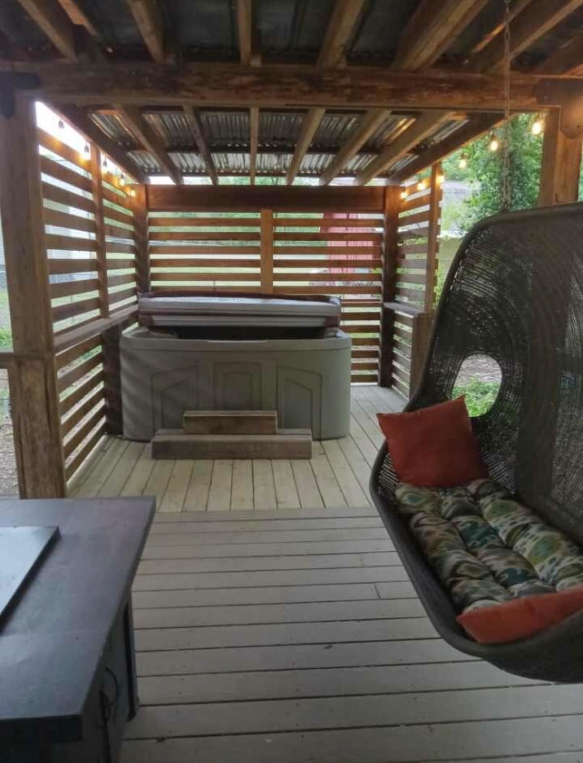 Covered tiny cabin deck with hot tub and hanging chair