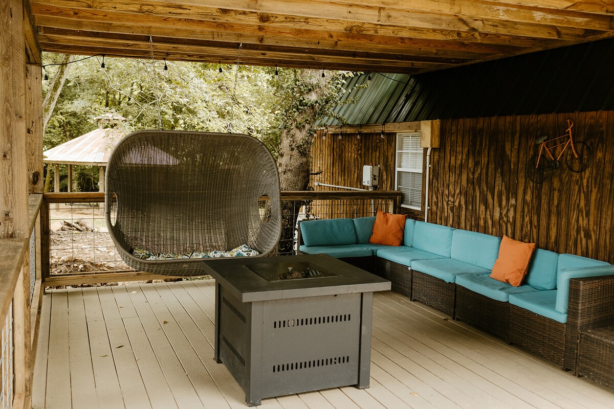Covered deck at the tiny cabin with outdoor seating and fire table
