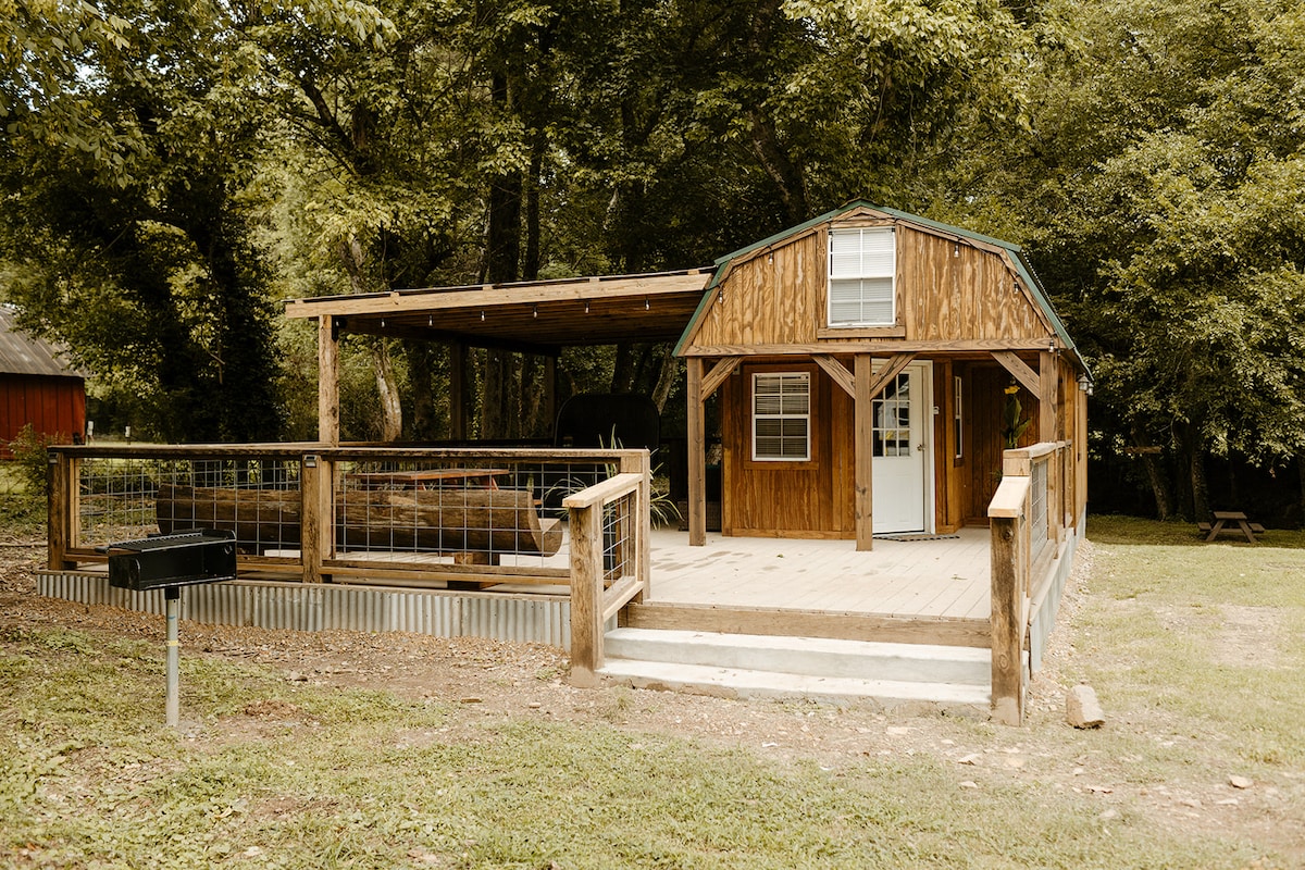 Front exterior of Running Water Tiny Cabin with a covered porch and wooded setting